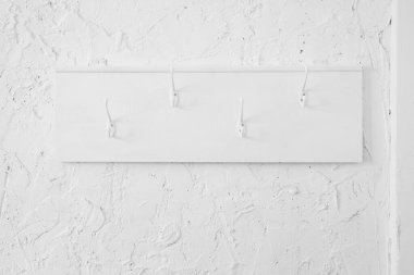 Beyaz ahşap elbise askısı ve desenli bir duvara asılı kancalar..