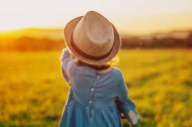 Bulanık sanat fotoğrafçılık. Şapkalı küçük kız gün batımı toplantısına koşuyor..