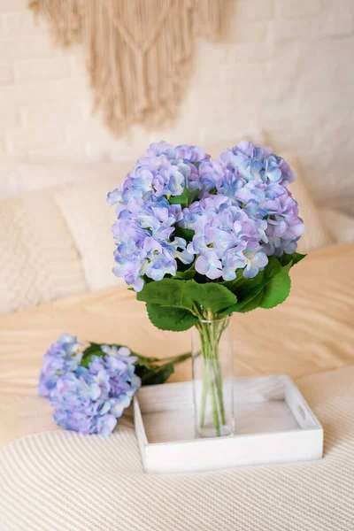 Bouquet of purple hydrangeas on a tray on the bed in the bedroom in the style of boho. Morning compliment.