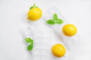 Limonlar, nane ve buz beyaz bir masada. Ev yapımı limonata soğutma malzemesi. Üst görünüm.