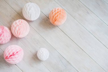Beyaz ahşap zeminde kağıt mendil bal peteği topları. Pembe parti dekorasyonu.