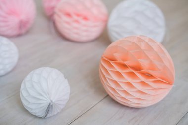 Beyaz ahşap zeminde kağıt mendil bal peteği topları. Pembe parti dekorasyonu.