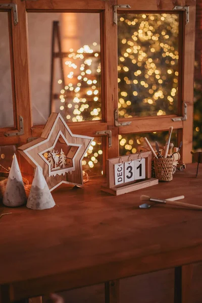 Tahta oyuncaklar atölyesi. Noel ağacındaki çelenklerin arka planındaki ahşap masa. Katlanan takvimde 31 Aralık.