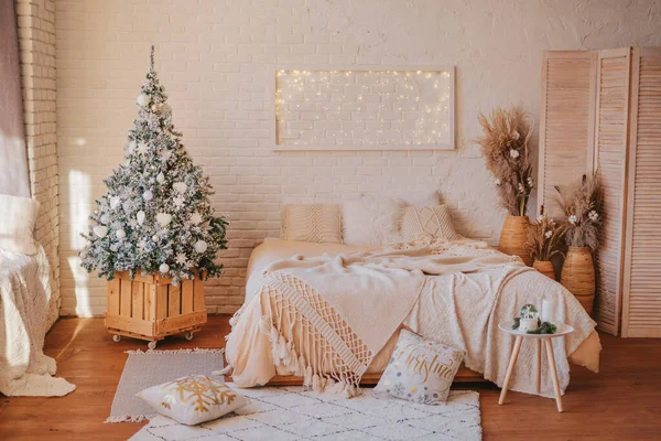 Konforlu, parlak bir yatak odası, yeni yıl süslemeleri, bir Noel ağacı, parlayan bir panel ve kabarık tekstil. Modern İskandinav iç mekanında Noel.