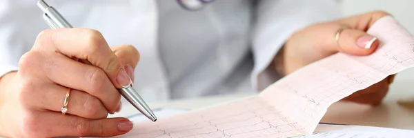 Dokter handen met cardiogram grafiek op Klembord pad — Stockfoto