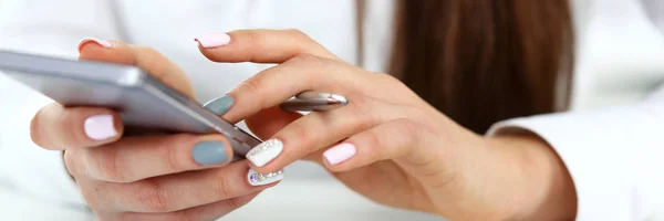 Vrouwelijke arm houden telefoon en zilveren pen op werkplek — Stockfoto