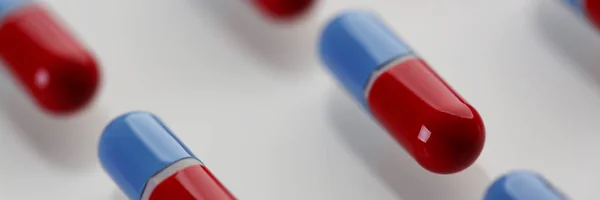 Pilha de comprimidos vermelhos e azuis dispostos em linha diagonal na mesa — Fotografia de Stock