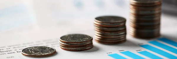 Montón de monedas de plata de pie en los papeles gráficos financieros —  Fotos de Stock