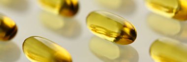 Sarı şeffaf omega-3 hapları çapraz çizgi halinde düzenlenmiş yığını