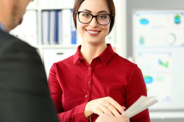 Gülümseyen güzel işkadını giyim gözlük kollarında finansal kağıtları tutun.