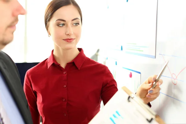 Schöne lächelnde Frau zeigt Arm in Finanzdiagramm — Stockfoto