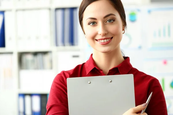 Bella ragazza sorridente in camicetta rossa sul posto di lavoro guardare in macchina fotografica — Foto Stock