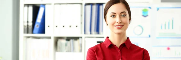 Mooi lachende meisje in de rode blouse op werkplek in de camera kijken — Stockfoto