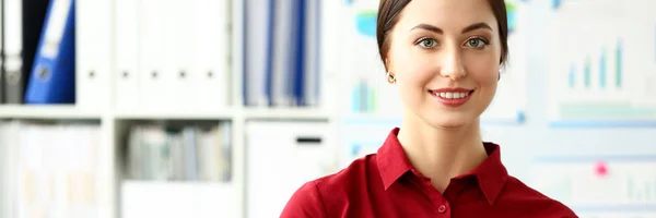 Bella ragazza sorridente in camicetta rossa sul posto di lavoro guardare in macchina fotografica — Foto Stock