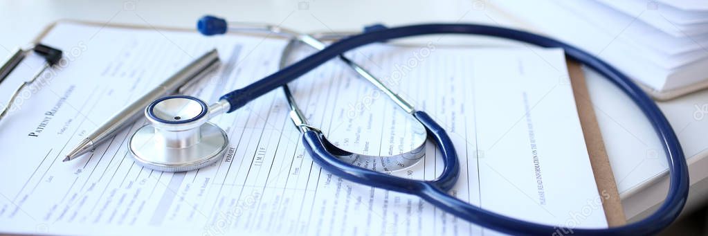 Stethoscope head and silver pen lying on medical application form