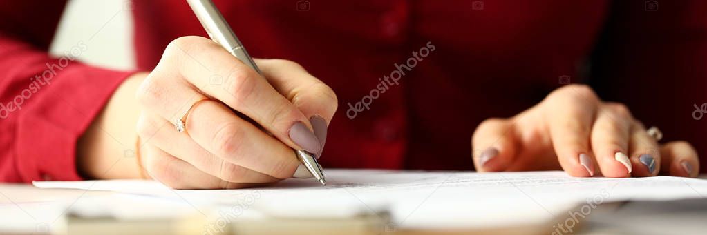 Female office worker holding silver pen filling out some application form
