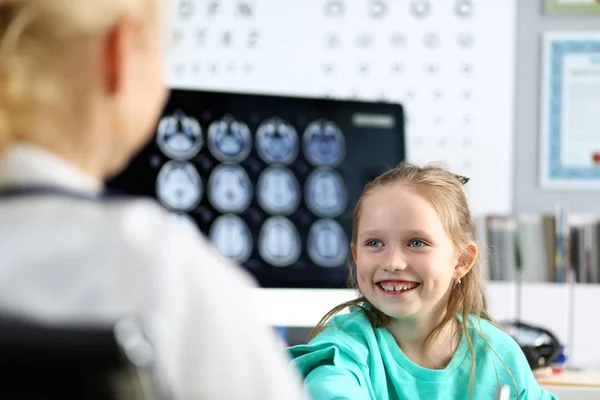 Sonriendo linda niña hablando con una doctora en su consultorio — Foto de Stock