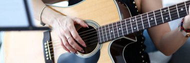 Evde kanepede oturan batı akustik gitar tutan kadın elleri