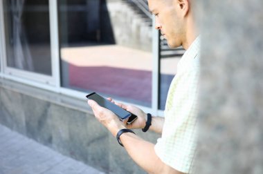 Elinde iki modern akıllı telefon tutan genç yakışıklı erkek