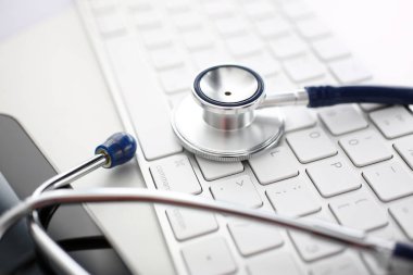 Doktor ofisinde gümüş klavye üzerinde yatan tıbbi stetoskop kafası çalışma masası