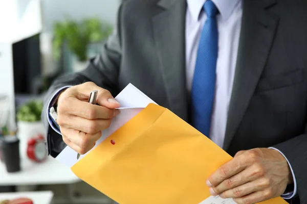 Clerk in suit and tie at workplace packing envelope unpacking envelope with important documentation