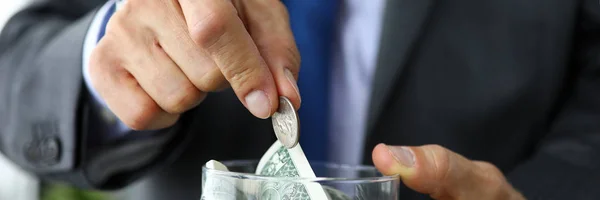 Rich man in suit and tie put extra coin into jar full of US dollars