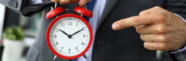 Man in suit and tie point finger to red vintage alarm clock face