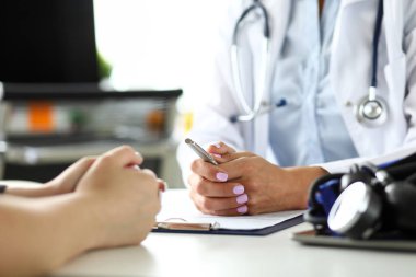 Sağlık şikayetlerini tartışan hasta ziyaretçiyi klinikte gören doktor