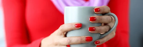 Female hands with red nails holding gray cup of coffee — Stock Photo, Image