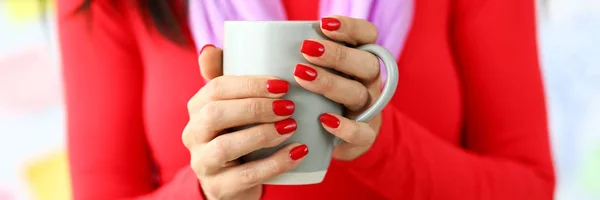 Kvinnliga händer med röda naglar som håller grå kopp kaffe — Stockfoto