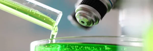 Mikroszkóp zöld anyaggal ömlött ki a kémcsőbe — Stock Fotó