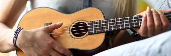 Female hands holding ukulele guitar learning how to play