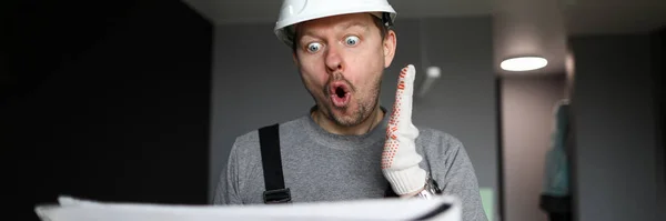 Geschockter Handwerker oder Ingenieur schaut sich Schema an — Stockfoto