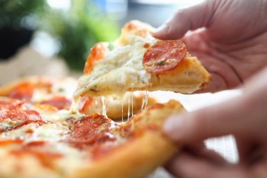 Erkek el, büyük lezzetli taze pizzayı tutuyor.