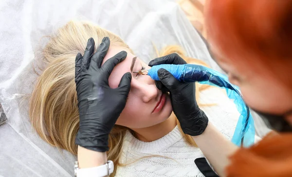 Girl lies in salon on procedure permanent eyebrow