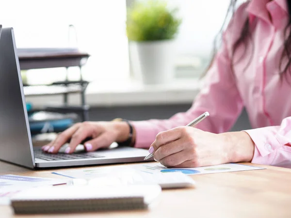 Büroangestellte schreibt Notizen und druckt auf Laptop — Stockfoto