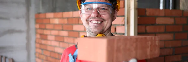 Szczęśliwy budowniczy trzyma cegły do muru i uśmiecha się — Zdjęcie stockowe
