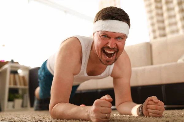 Homem em casa no tapete faz uma prancha de exercício — Fotografia de Stock