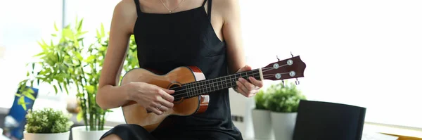Kreativ tjej i svart klänning spelar gitarr — Stockfoto