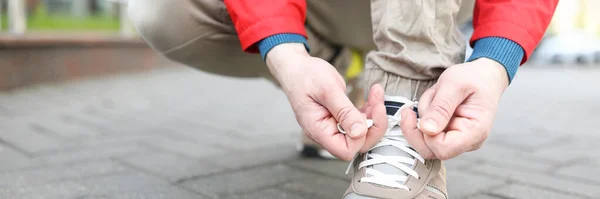 Der Typ in der Jacke bindet Schnürsenkel an Stiefel — Stockfoto