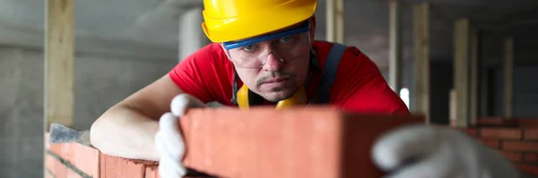 Construtor cuidadosamente coloca tijolo vermelho na alvenaria — Fotografia de Stock