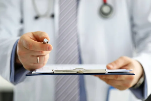 Hand of male GP passing to patient silver pen asking to sign some documents