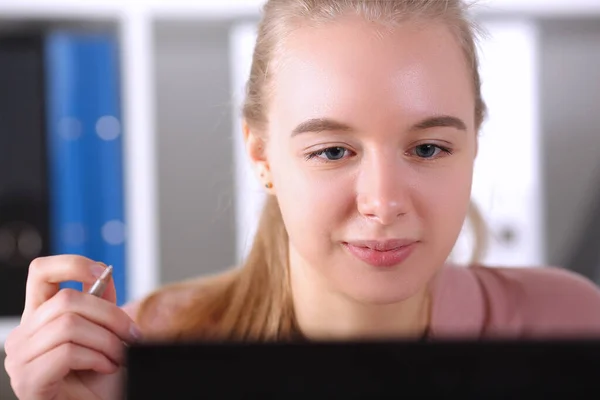 Chica inteligente mira el monitor de la computadora y sostiene la pluma —  Fotos de Stock