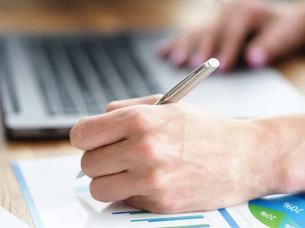 Man hemma gör anteckningar i rapporten nära laptop — Stockfoto