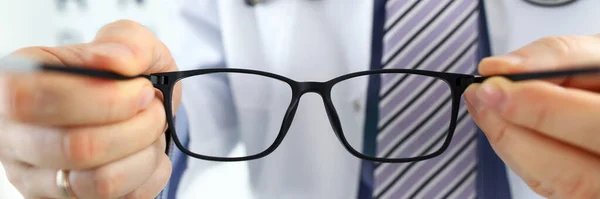 Hombre medicina doctor manos dando par de negro gafas — Foto de Stock
