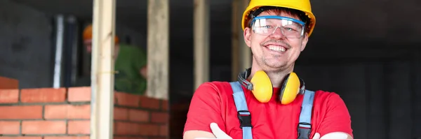Construtor feliz fica perto de alvenaria e sorri — Fotografia de Stock