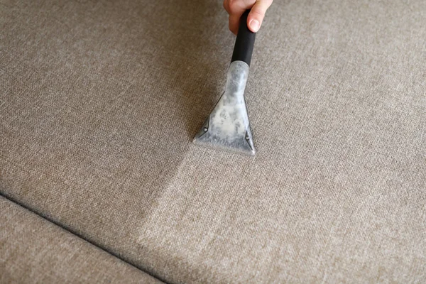 Laki-laki pembantu rumah tangga membersihkan sofa dengan mengisap mencuci — Stok Foto