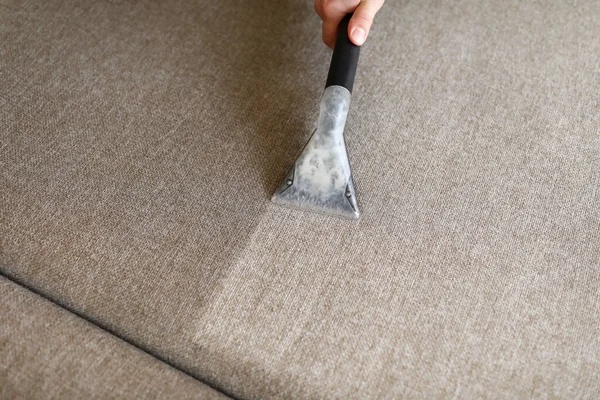 Male housekeeper hand cleaning sofa with washing suction — Stock Photo, Image