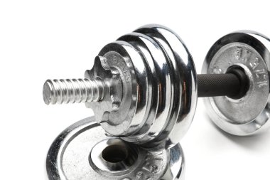 Gümüş renkli, parlak, metal bir halter yığını üzerinde duruyor.