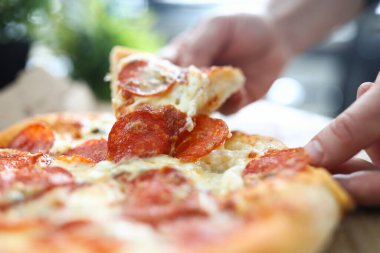 Erkek el, büyük lezzetli taze pizzayı tutuyor.